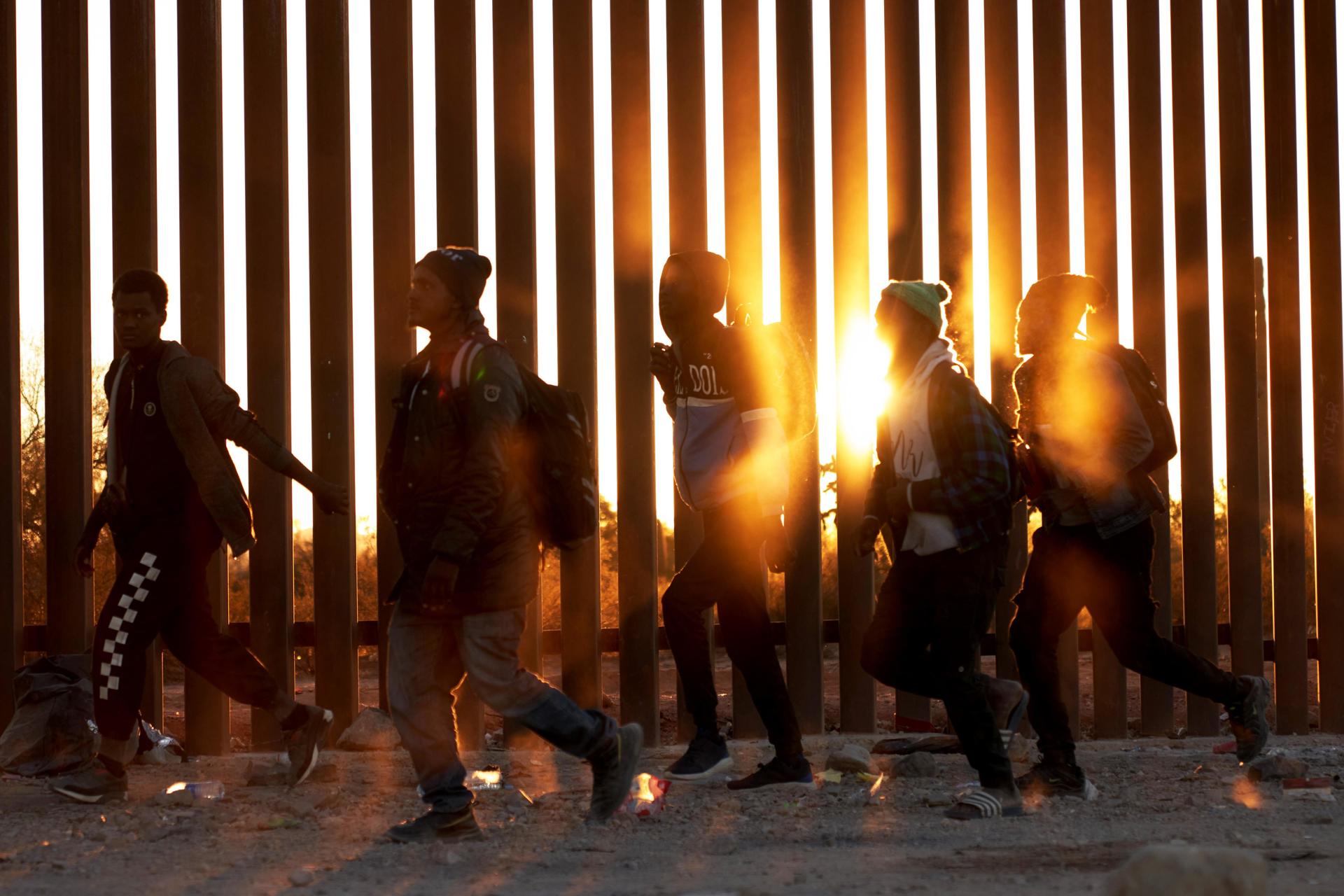 Fotografía de archivo de migrantes que caminan junto al muro en la frontera de EE.UU, y México, en Lukeville, Arizona, EE.UU. EFE/ Allison Dinner