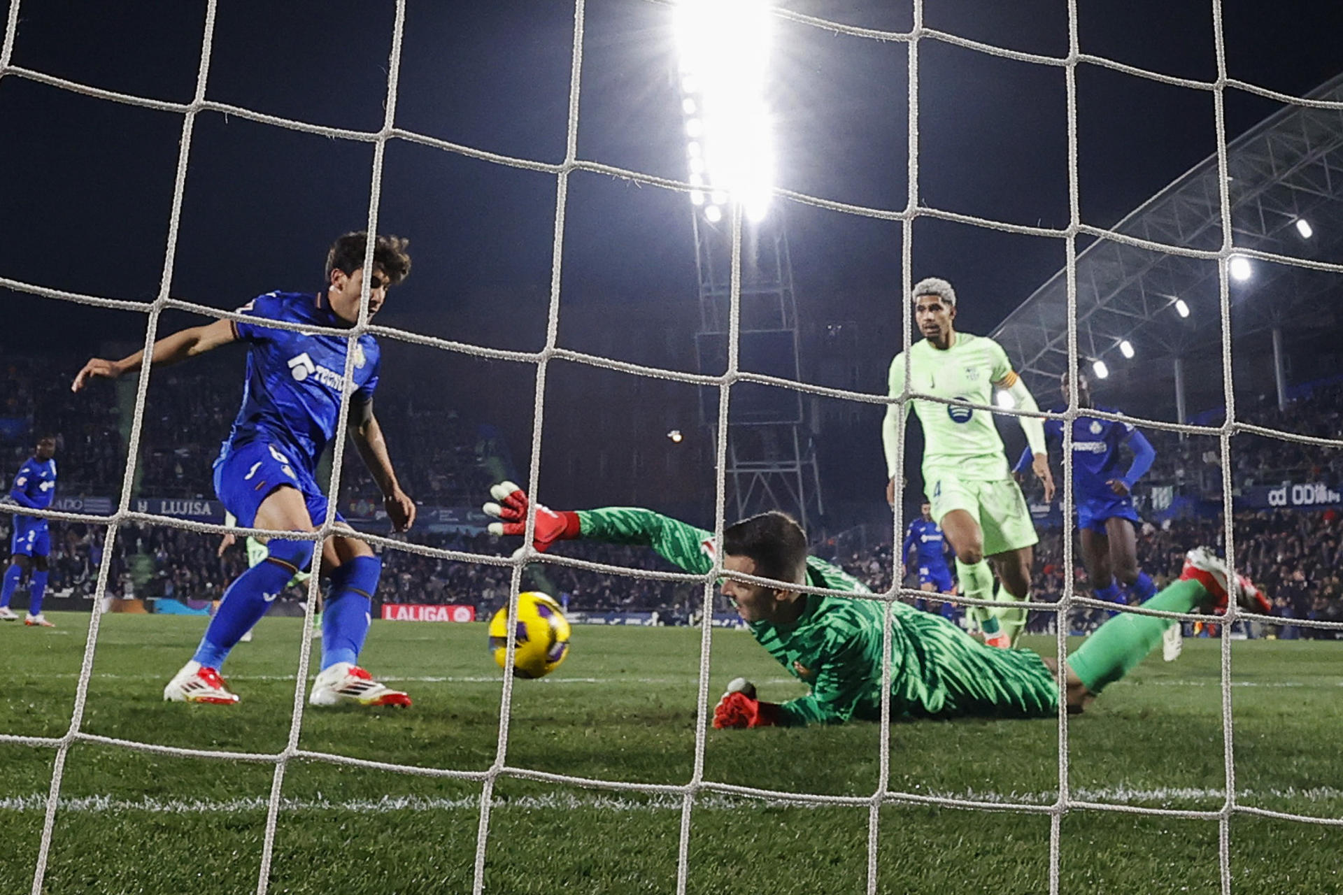 El guardameta del FC Barcelona, Iñaki Peña (d), intenta detener el balón rematado por el centrocampista uruguayo del Getafe, Mauro Arambarri, en la jugada que ha significado el primer gol del equipo madrileño durante el encuentro correspondiente a la jornada 20 de Laliga EA Sports que disputaron Getafe y FC Barcelona en el Coliseum de Getafe. EFE / Chema Moya..