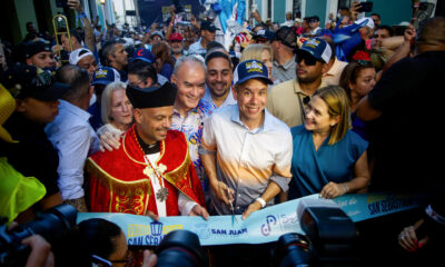 El alcalde de San Juan, Miguel Romero (c) y el capellán de la Catedral de San Juan, el padre Benjamín Pérez (i), cortan la cinta de la inauguración de la edición 55 de las Fiestas de la Calle San Sebastián este jueves, en San Juan (Puerto Rico). EFE/ Thais Llorca