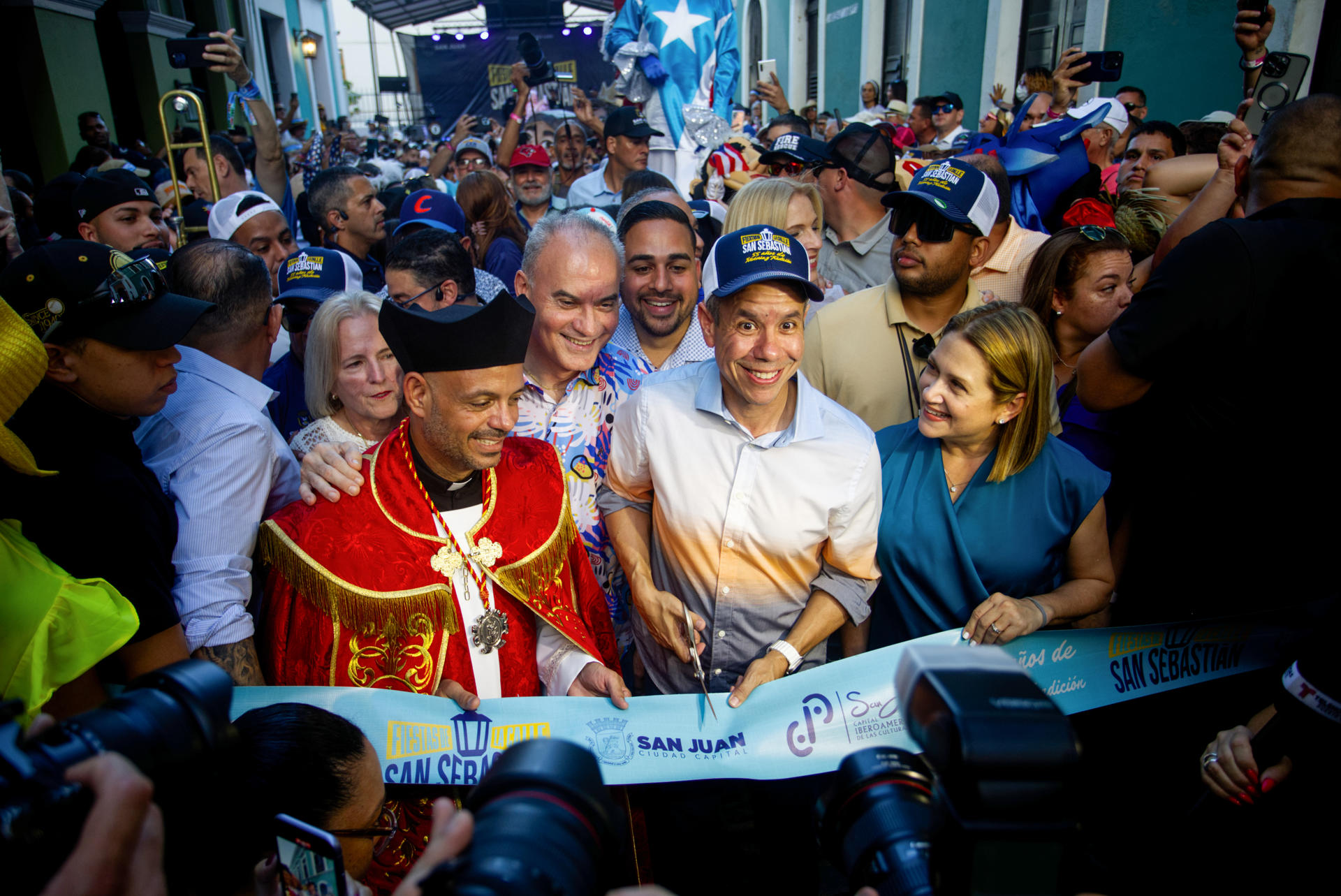 El alcalde de San Juan, Miguel Romero (c) y el capellán de la Catedral de San Juan, el padre Benjamín Pérez (i), cortan la cinta de la inauguración de la edición 55 de las Fiestas de la Calle San Sebastián este jueves, en San Juan (Puerto Rico). EFE/ Thais Llorca