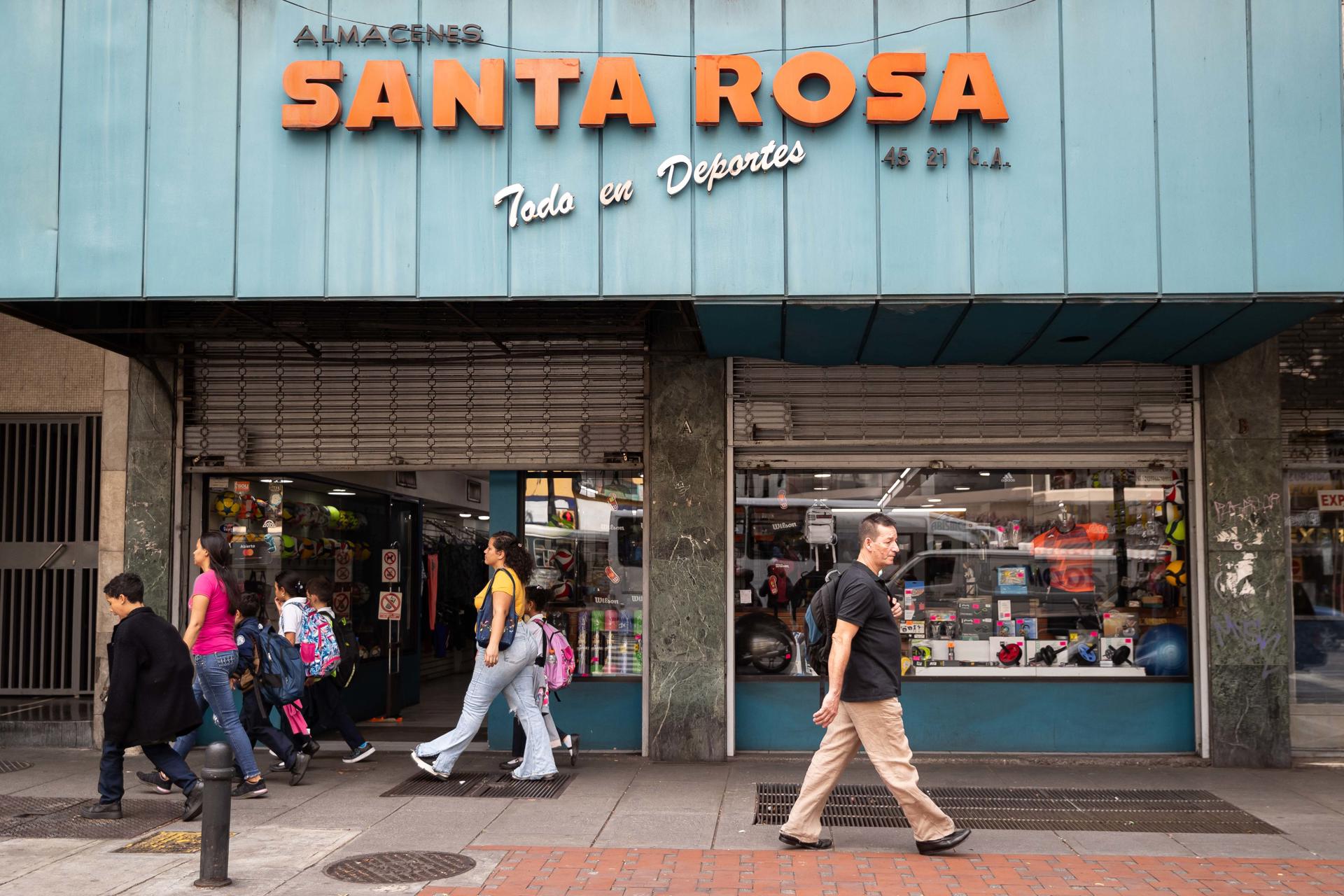 Varias personas caminan frente a un comercio este martes 14 de enero de 2025, en Caracas (Venezuela). EFE/ Ronald Peña R.