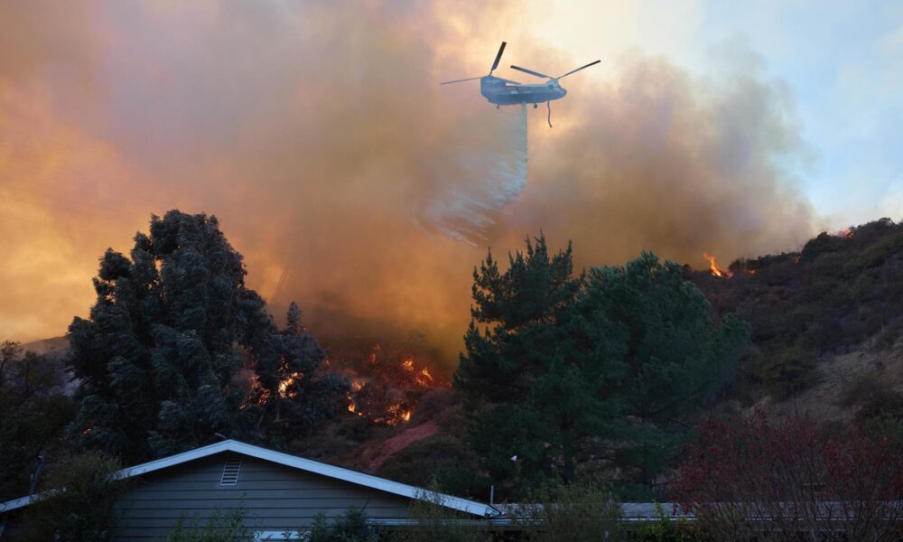 Un helicóptero arroja agua sobre una casa durante el incendio forestal de Palisades en Los Ángeles, California (EE.UU.). EFE/ALLISON DINNER