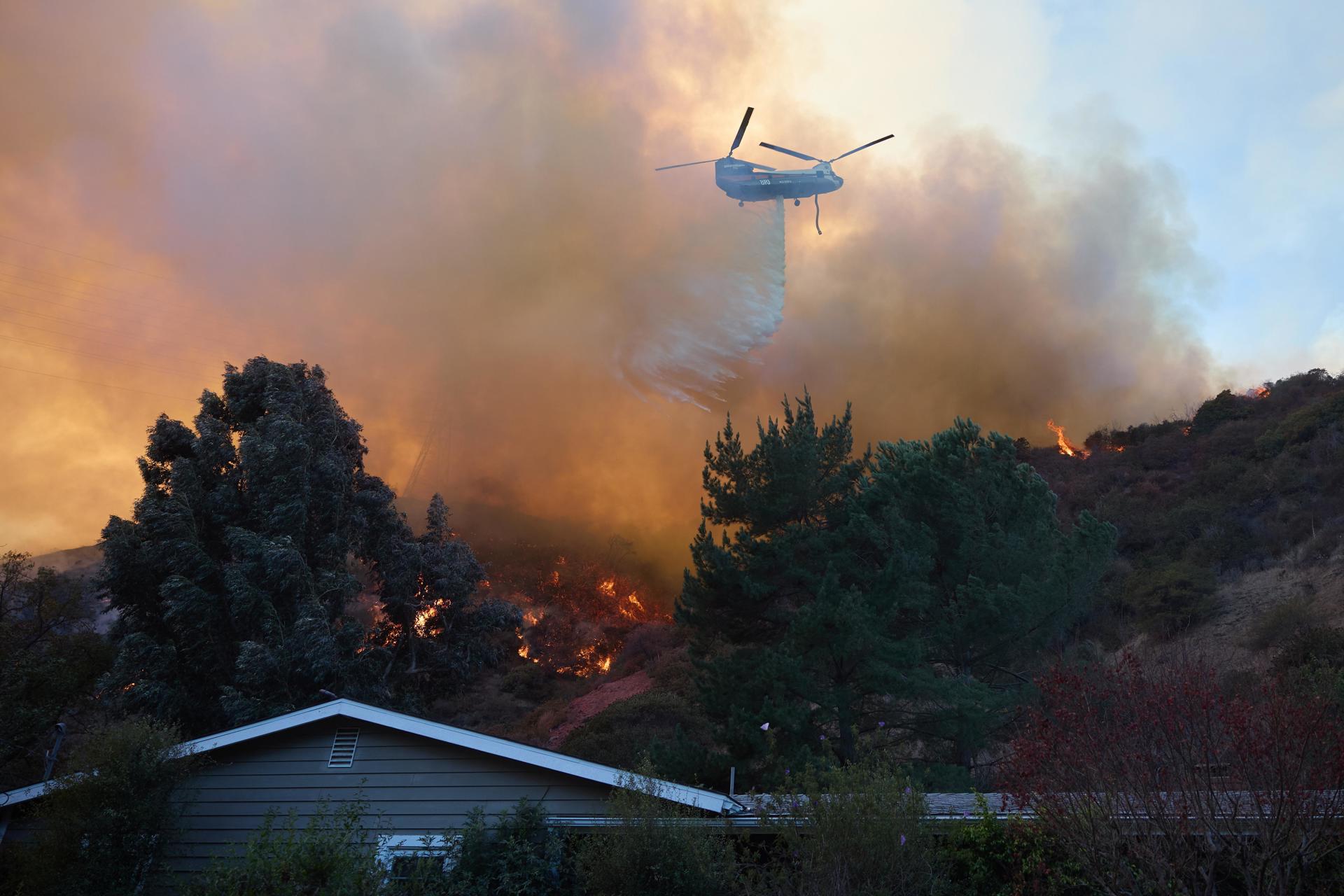 Un helicóptero arroja agua sobre una casa durante el incendio forestal de Palisades en Los Ángeles, California (EE.UU.). EFE/ALLISON DINNER