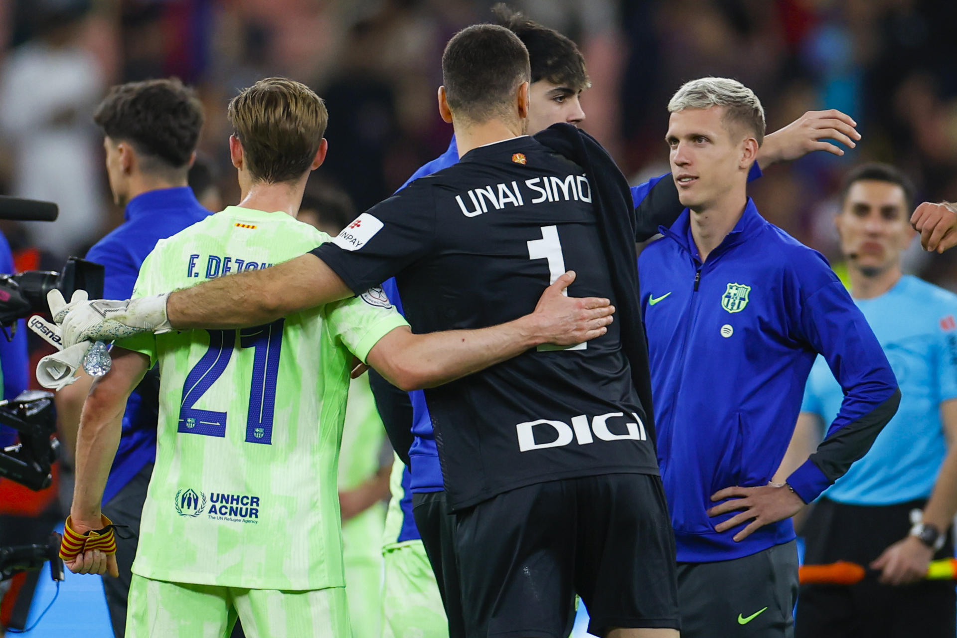 Los jugadores del FC Barcelona, Dani Olmo (d) y el neerlandés Frenkie de Jong (i), se saludan con el guardameta del Athletic Club, Unai Simón, a la finalización del partido de semifinales de la Supercopa de España de fútbol en el estadio Rey Abdullah de Yeda, en Arabia Saudí. EFE/Alberto Estévez