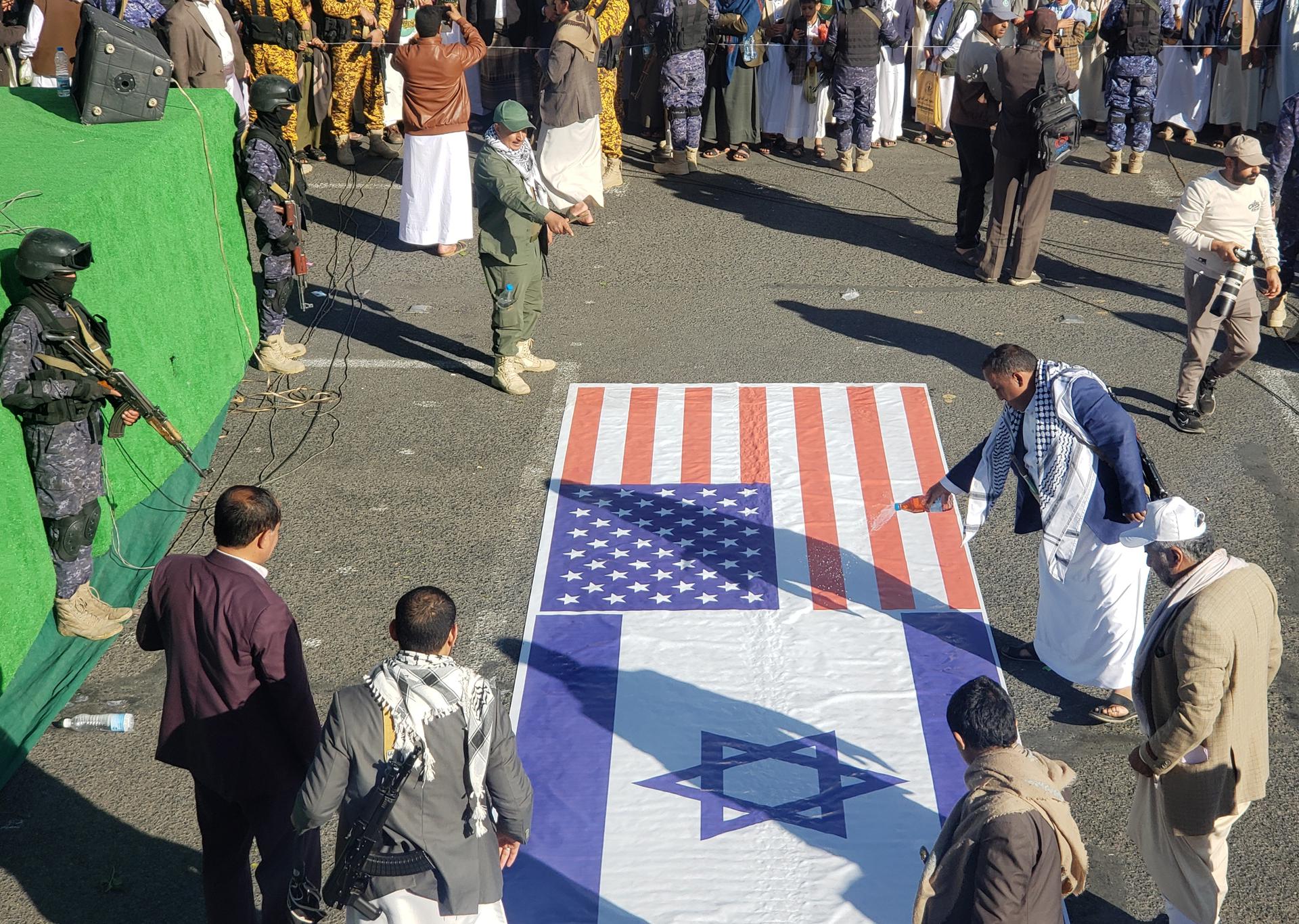 Los partidarios de los hutíes mojan una pancarta con las banderas de EE. UU. e Israel durante una protesta contra EE. UU. y contra Israel en Saná, Yemen, el 10 de enero de 2025. Miles de partidarios de los hutíes se reunieron en Sana'a para protestar contra los ataques de Estados Unidos e Israel que apuntan a sitios controlados por los hutíes en Yemen, en medio de la escalada de los ataques hutíes contra Israel y la navegación comercial en los mares alrededor de Yemen, en represalia por los continuos ataques militares israelíes en la Franja de Gaza. (Protestas) EFE/EPA/YAHYA ARHAB