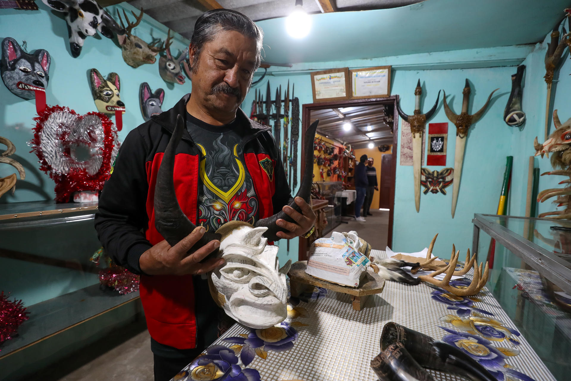 Fotografía del 6 de enero de 2025 del artesano Ángel Velasco observando una mascara en Píllaro (Ecuador). EFE/José Jácome