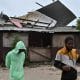 Personas pasan frente a una casa afectada por los vientos preliminares del huracán Melissa este lunes, en la playa pesquera de Hellshire, en Portmore (Jamaica). EFE/Rudolph Brown