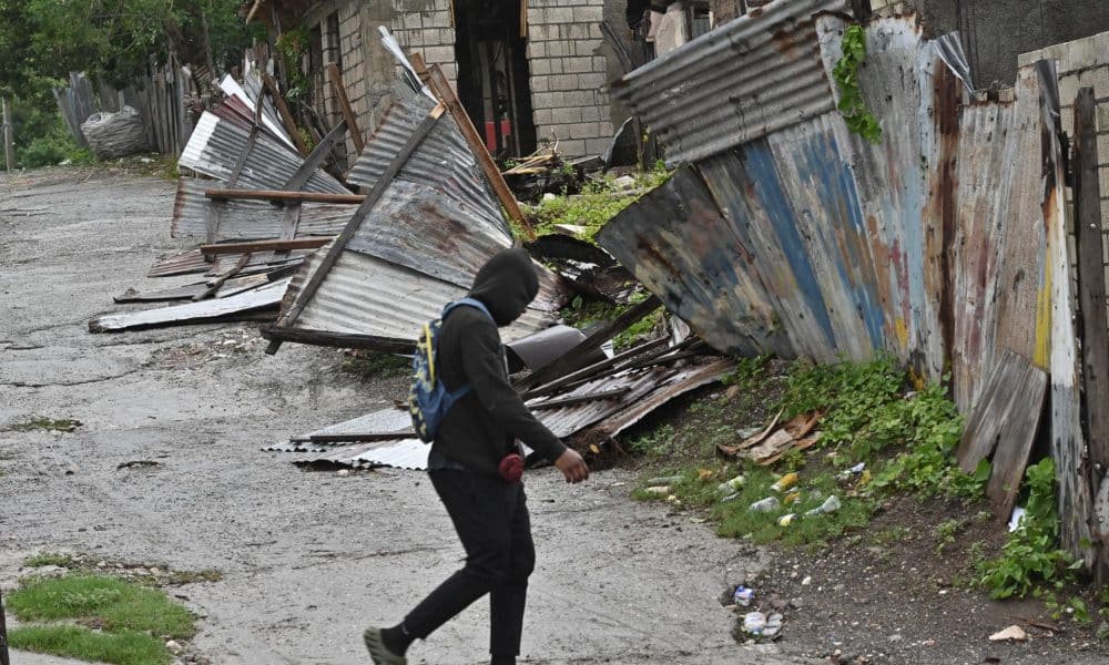 Una persona camina frente a una casa afectada por el paso del huracán Melissa este martes, en Kingston (Jamaica). EFE/Rudolph Brown