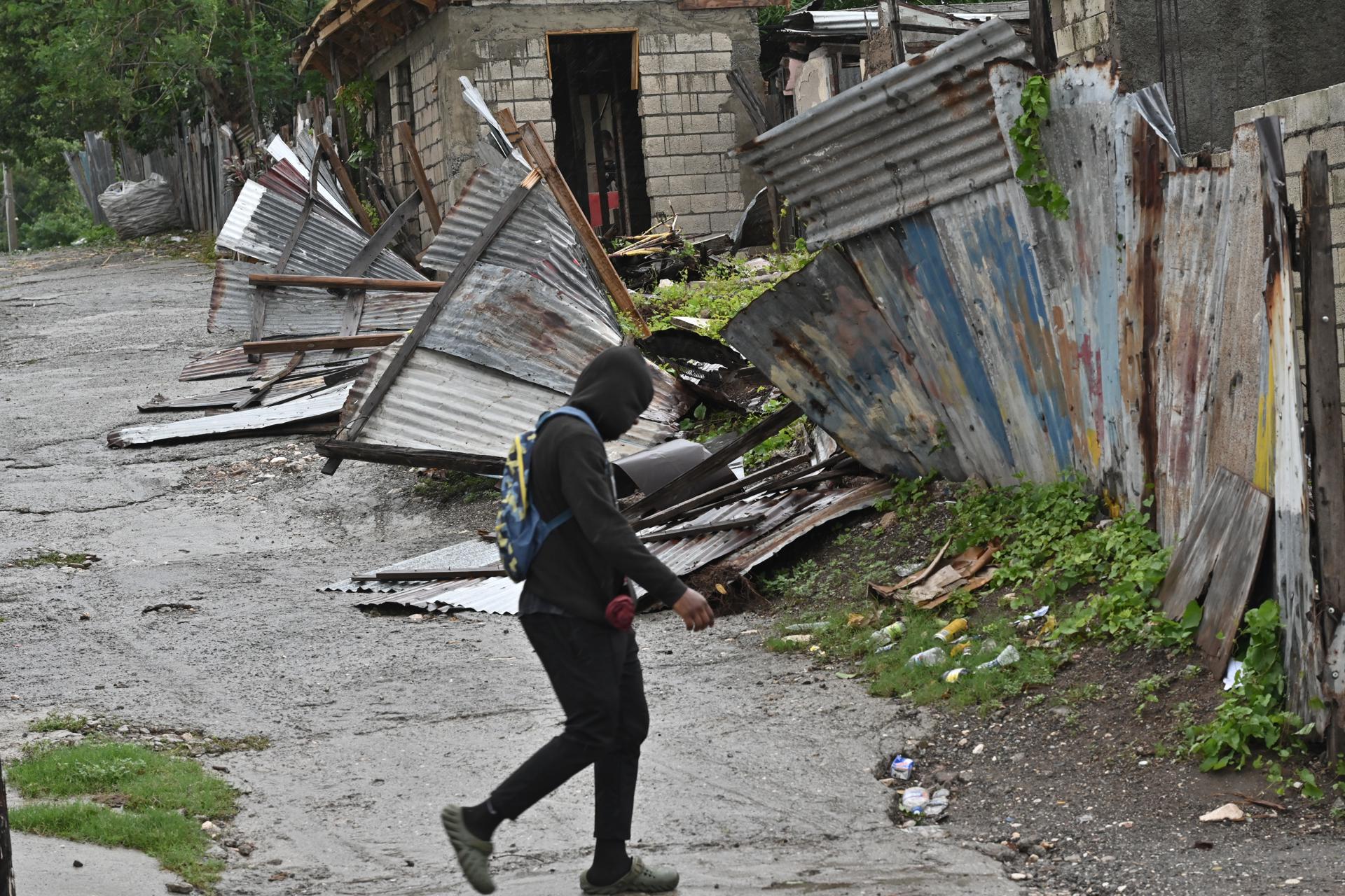 Una persona camina frente a una casa afectada por el paso del huracán Melissa este martes, en Kingston (Jamaica). EFE/Rudolph Brown