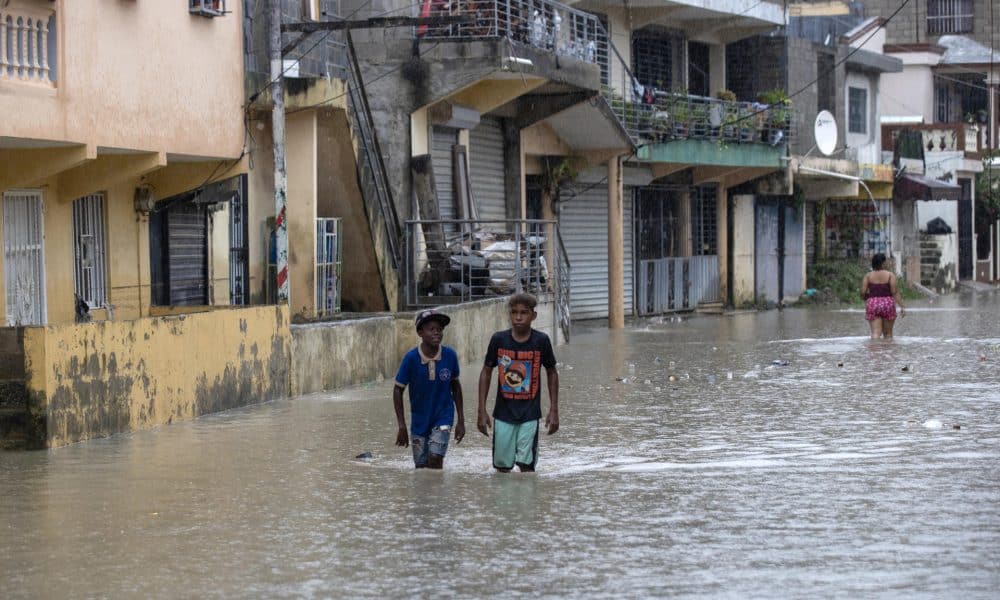 Personas caminan por una calle inundada en el barrio Manoguayabo este viernes, en Santo Domingo (República Dominicana). EFE/Orlando Barría
