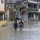 Personas caminan por una calle inundada en el barrio Manoguayabo este viernes, en Santo Domingo (República Dominicana). EFE/Orlando Barría