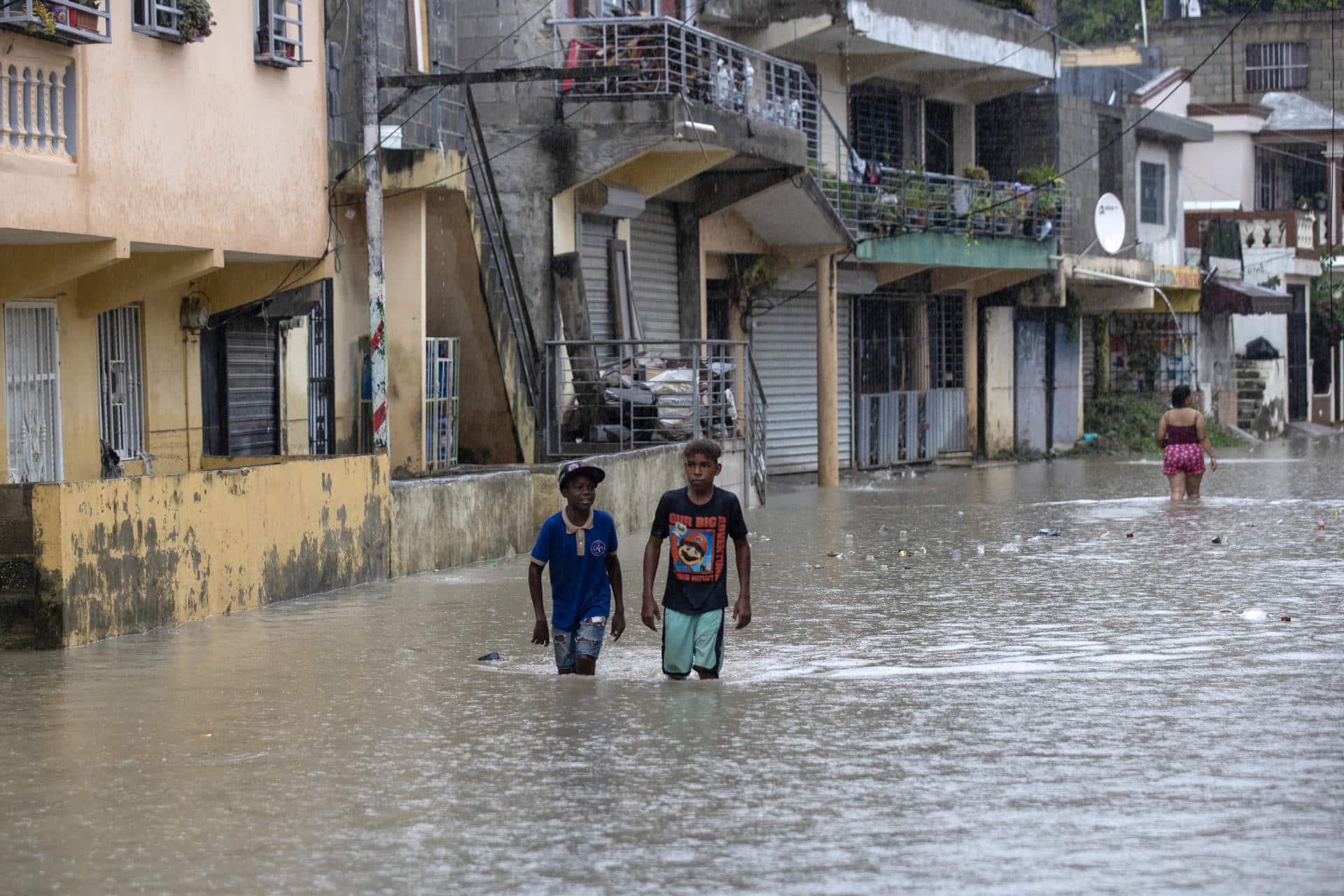 Personas caminan por una calle inundada en el barrio Manoguayabo este viernes, en Santo Domingo (República Dominicana). EFE/Orlando Barría