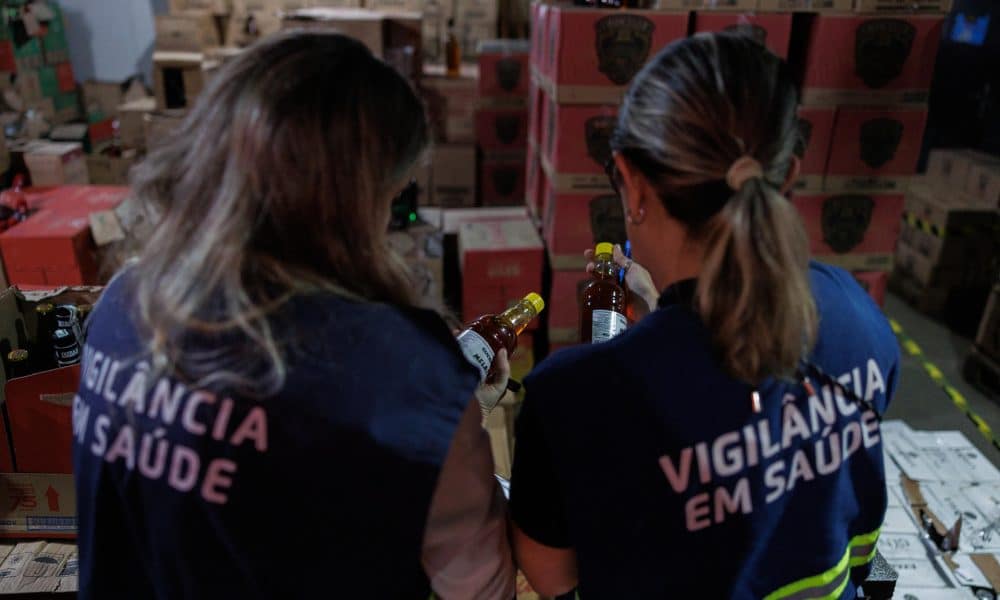 Fotografía de archivo, tomada el pasado 2 de octubre, en la que se captó a un par de agentes de vigilancia sanitaria al revisar botellas de licor, durante un operativo en contra de destilados adulterados, en una bodega del sur de São Paulo (Brasil). EFE/Isaac Fontana
