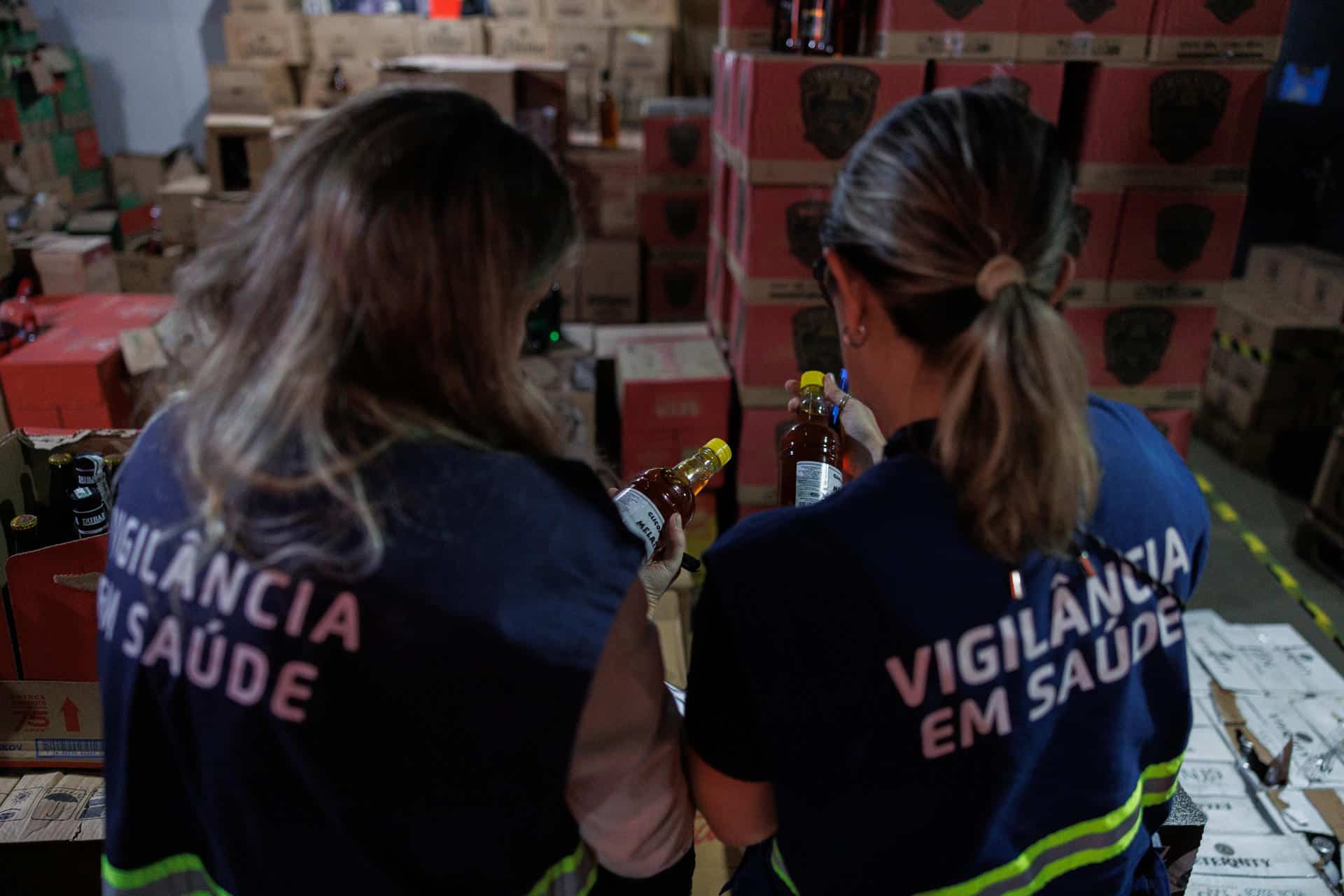 Fotografía de archivo, tomada el pasado 2 de octubre, en la que se captó a un par de agentes de vigilancia sanitaria al revisar botellas de licor, durante un operativo en contra de destilados adulterados, en una bodega del sur de São Paulo (Brasil). EFE/Isaac Fontana