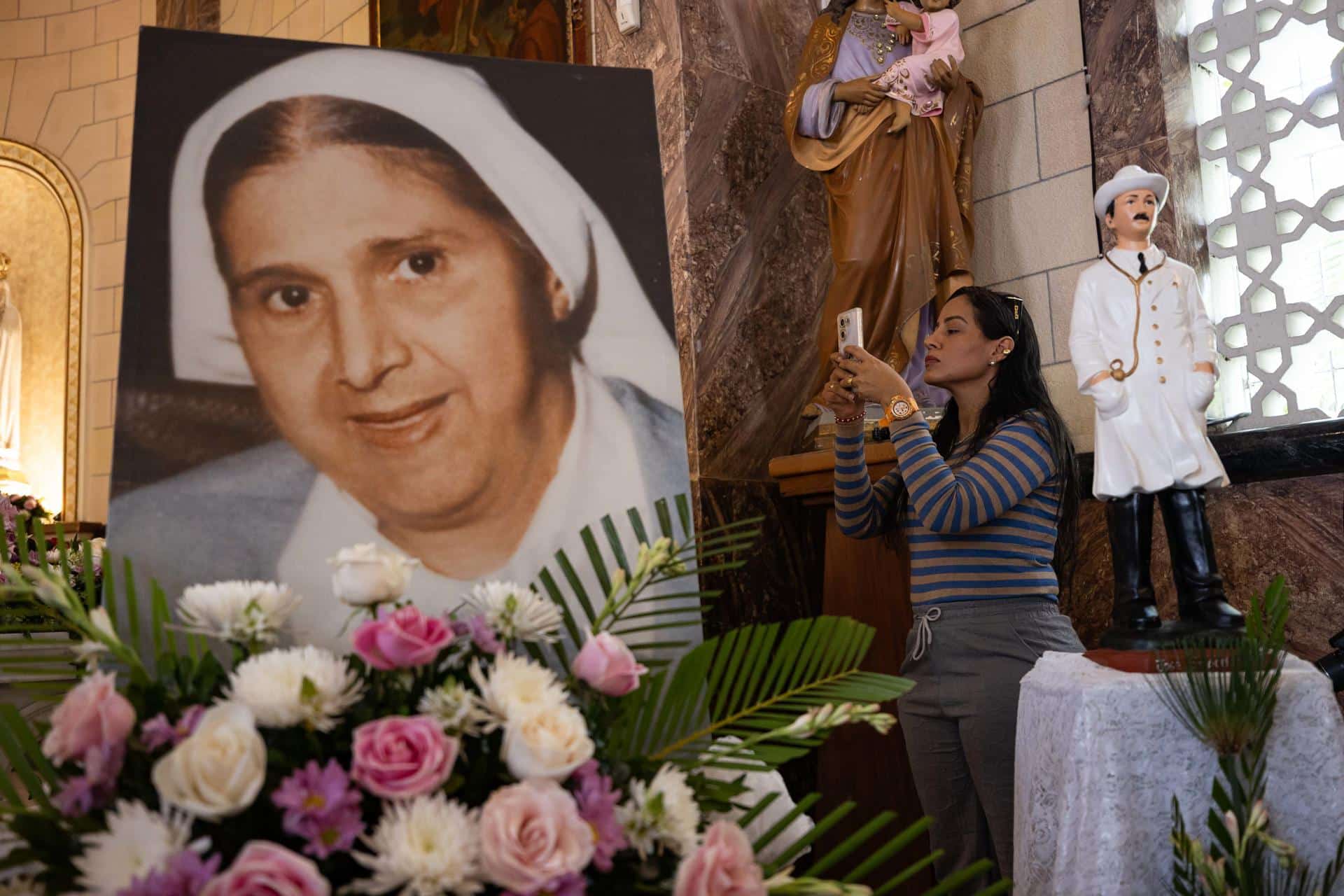 Una mujer toma una fotografía a una imagen de Santa Carmen Rendiles durante una misa en su honor este domingo, en Caracas (Venezuela). EFE/ Ronald Peña R