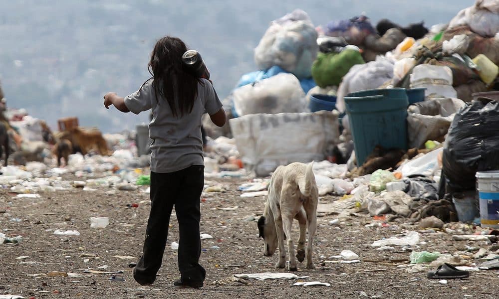 Fotografía de archivo de un niño con su perro caminando rumbo a su casa entre montañas de basura en el vertedero municipal del Bordo de Xochiaca, en Ciudad Nezahualcoyotl (México). EFE/Alex Cruz