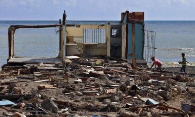 Personas caminan frente a una casa destruida, este jueves en el poblado de Guamá, Santiago de Cuba (Cuba). EFE/ Ernesto Mastrascusa