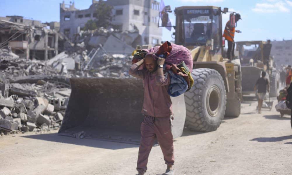 Un hombre con un hatillo con sus pertenencias pasa ante varias excavadoras del Ayuntamiento de la ciudad de Gaza que comienza este martes las operaciones de remoción de escombros y apertura de las calles principales de la capital gazatí para despejarlas y prepararlas para su uso, tras dos años de bombardeos. EFE/ Ahmad Awad