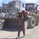 Un hombre con un hatillo con sus pertenencias pasa ante varias excavadoras del Ayuntamiento de la ciudad de Gaza que comienza este martes las operaciones de remoción de escombros y apertura de las calles principales de la capital gazatí para despejarlas y prepararlas para su uso, tras dos años de bombardeos. EFE/ Ahmad Awad