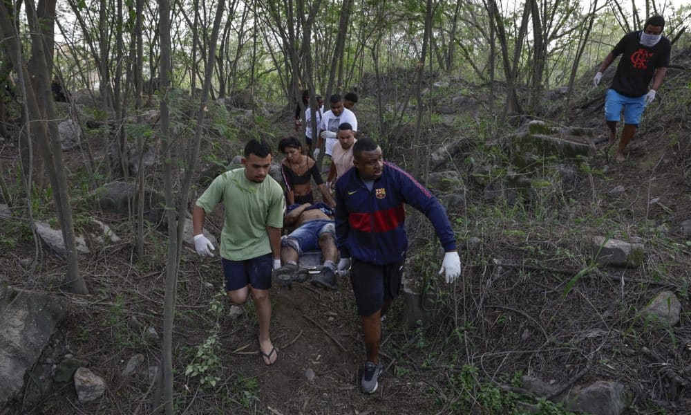 Personas retiran un cuerpo sin vida de una zona boscosa este miércoles, en la favela Vila Cruzeiro en Río de Janeiro (Brasil). EFE/ André Coelho