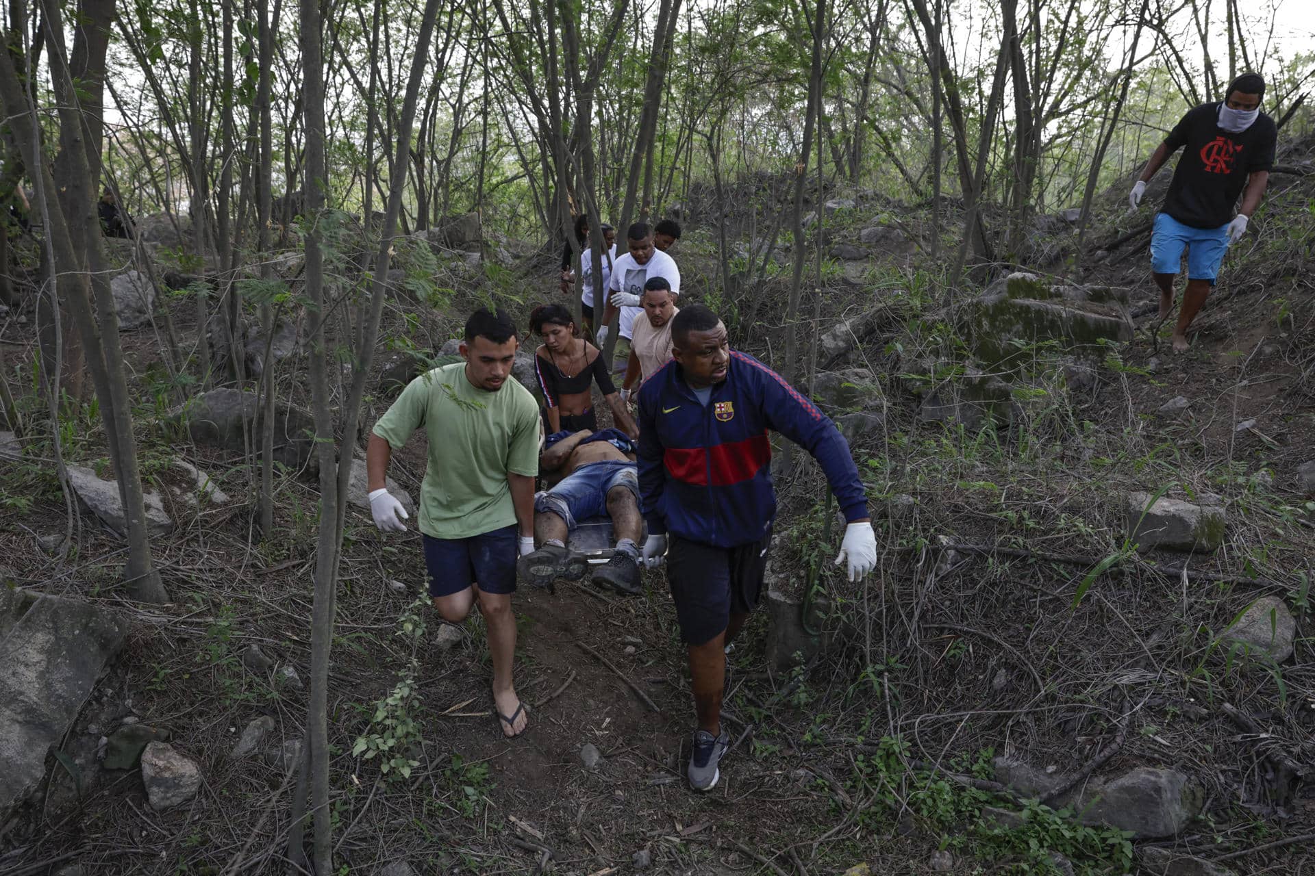 Personas retiran un cuerpo sin vida de una zona boscosa este miércoles, en la favela Vila Cruzeiro en Río de Janeiro (Brasil). EFE/ André Coelho