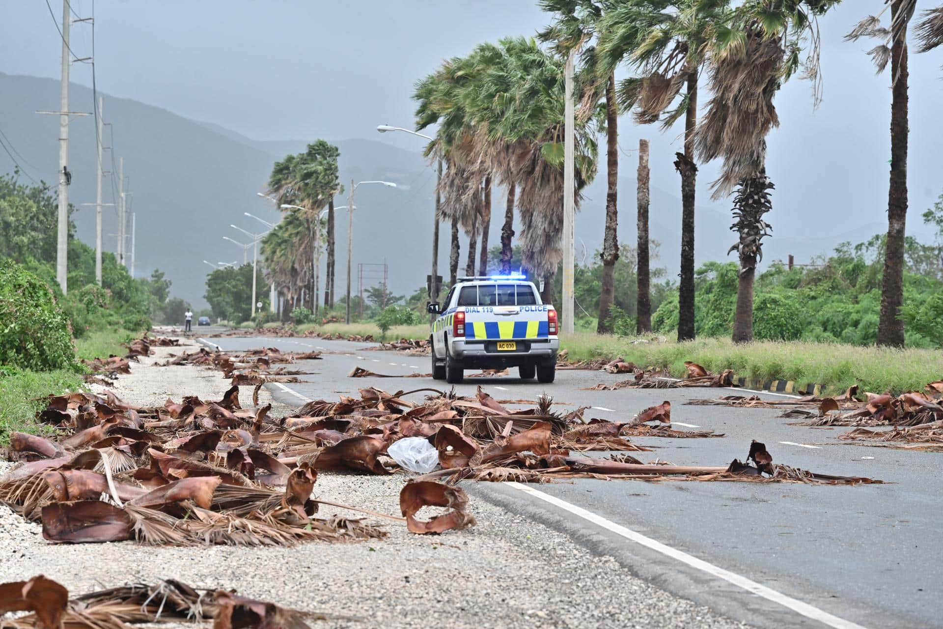 Un vehículo de la policía patrulla una carretera llena de escombros de árboles debido al paso del huracán Melissa, en Kingston (Jamaica). EFE/Rudolph Brown