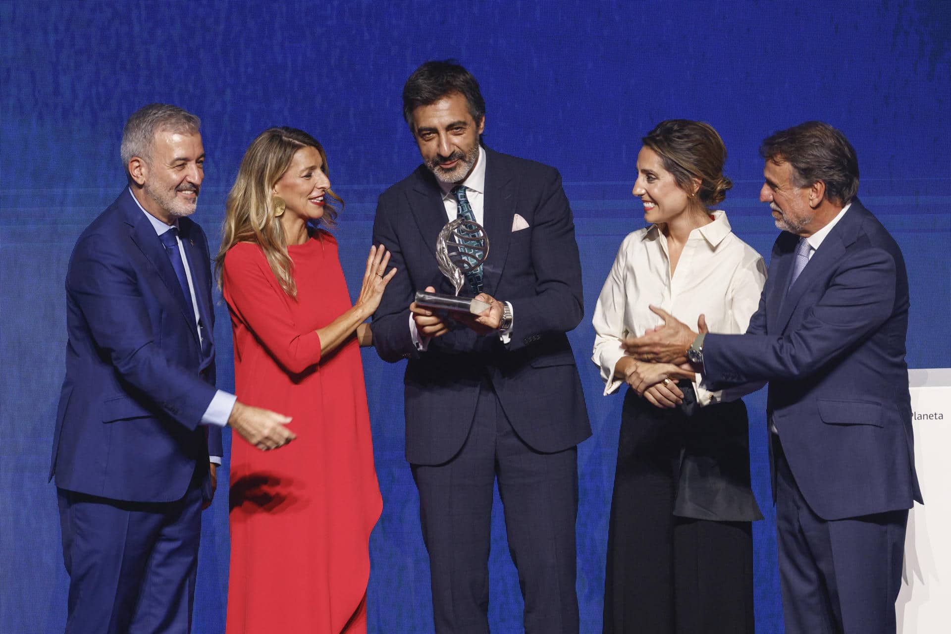 El escritor Juan del Val (c) acompañado por el alcalde de Barcelona, Jaume Collbini (i), la ministra de Trabajo, Yolanda Díaz (2i), la escritora Ángeles Banzas y el presidente del Grupo Planeta, José Creuheras, tras recibir el premio Planeta por la novela 'Vera, una historia de amor' durante la gala celebrada este miércoles en Barcelona. EFE/Quique García