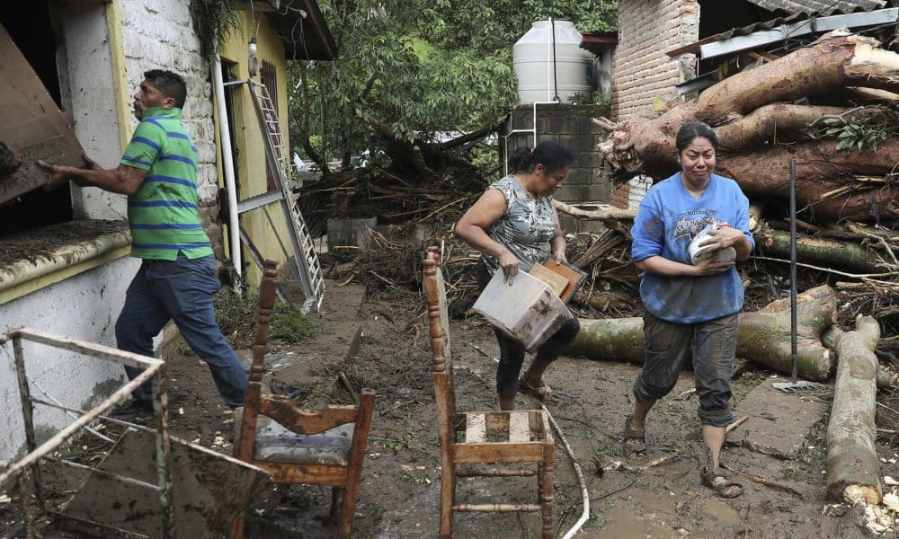 Personas caminan frente a casas afectadas por inundaciones en la aldea Rio Abajo este viernes, en Tegucigalpa (Honduras).EFE/ Gustavo Amador