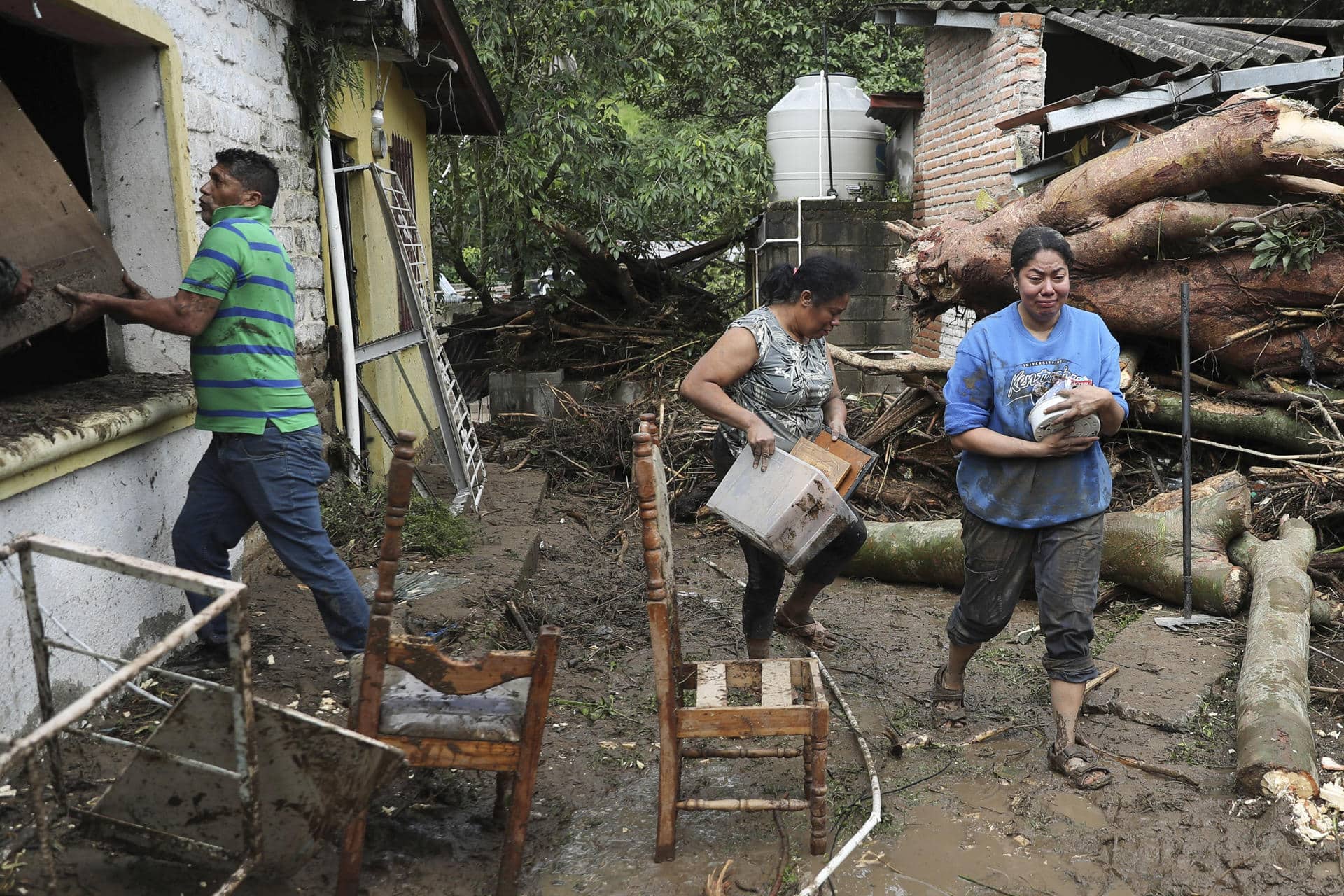 Personas caminan frente a casas afectadas por inundaciones en la aldea Rio Abajo este viernes, en Tegucigalpa (Honduras).EFE/ Gustavo Amador