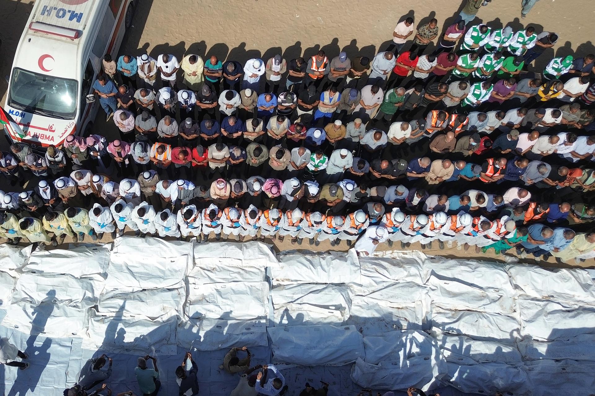 Equipos médicos rezan junto a los restos y cuerpos de palestinos no identificados, devueltos por Israel, antes de su entierro masivo fuera del Hospital Nasser en Khan Yunis, Franja de Gaza sur, 22 de octubre de 2025. La devolución de prisioneros palestinos fallecidos por Israel forma parte de un acuerdo de alto el fuego entre Israel y Hamas que entró en vigor el 10 de octubre de 2025. EFE/EPA/HAITHAM IMAD