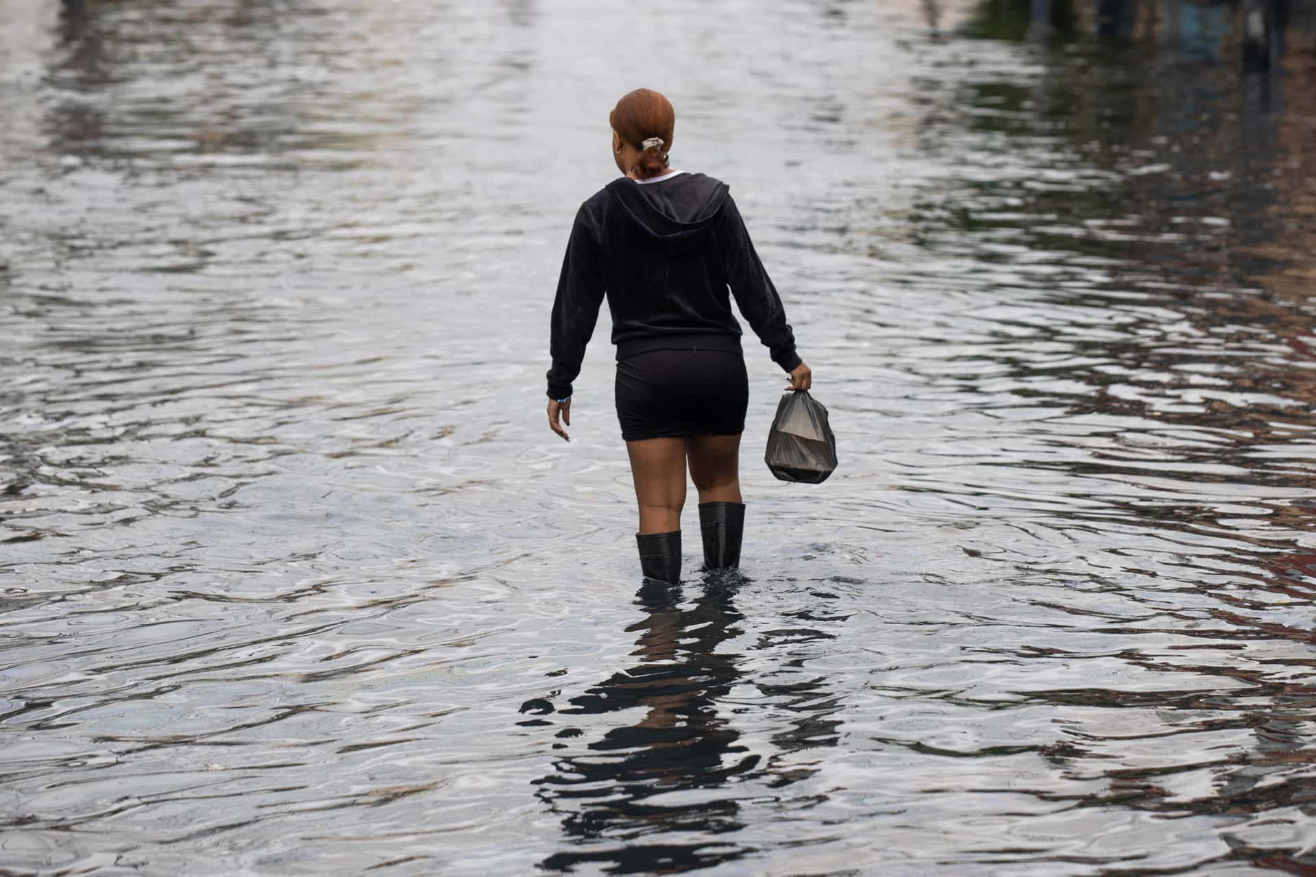 Una mujer camina por una zona inundada este jueves, en Santo Domingo (República Dominicana). EFE/ Orlando Barría