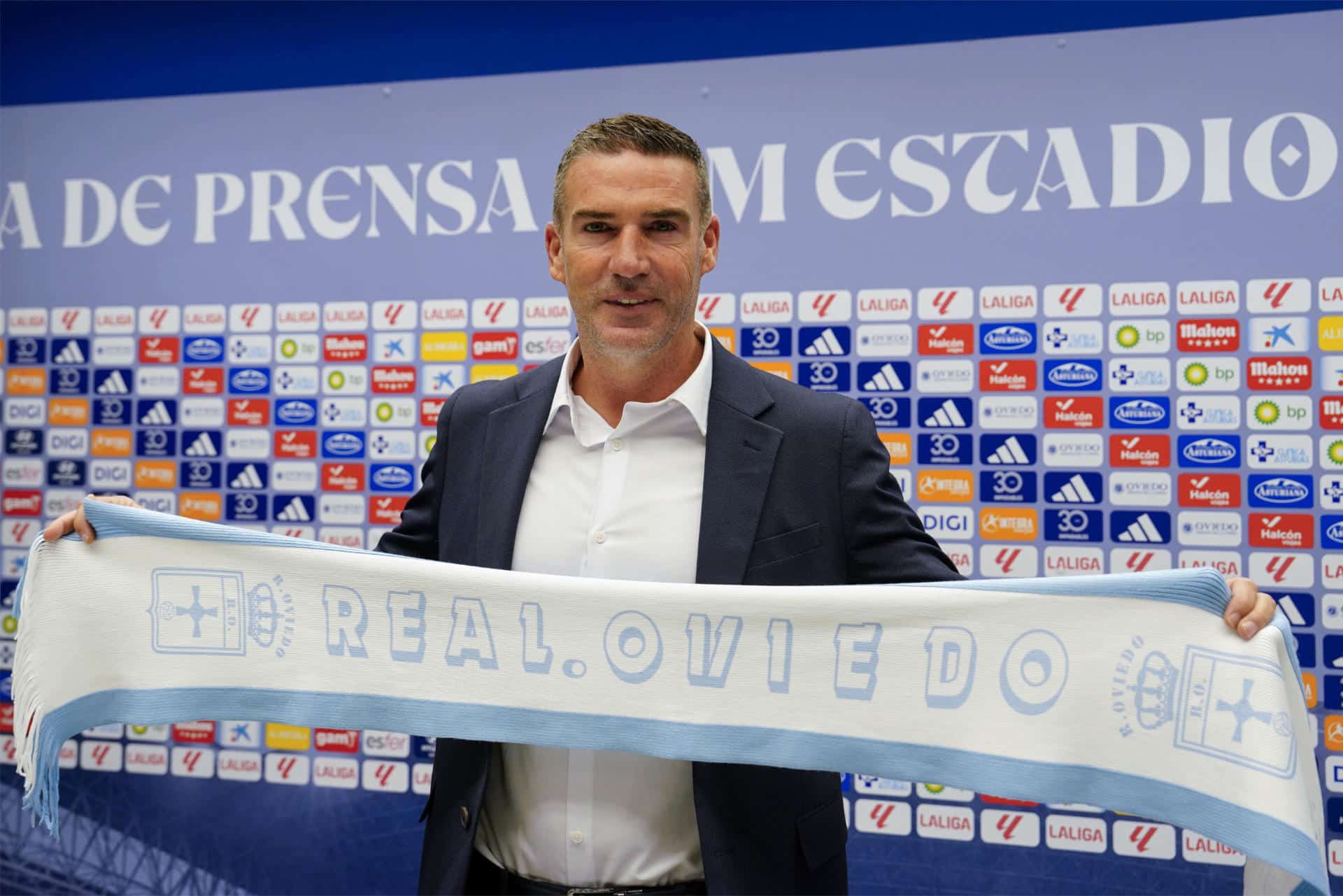 El nuevo entrenador del Oviedo, Luis Carrión, posa con una bufanda del club durante su presentación oficial, este viernes en el estadio Carlos Tartiere de la capital asturiana. EFE/Paco Paredes