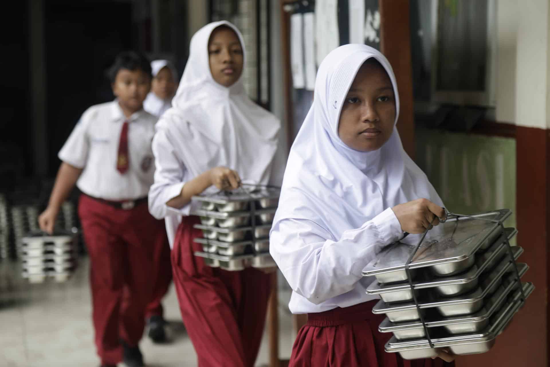 Estudiantes indonesios cargan bandejas de comida gratuita en una escuela primaria en Depok, Java Occidental, Indonesia, el 19 de agosto de 2025, en el marco del programa insignia del presidente Prabowo Subianto, por el que más de 6.000 niños han sufrido intoxicaciones alimentarias desde su lanzamiento en enero. EFE/EPA/BAGUS INDAHONO