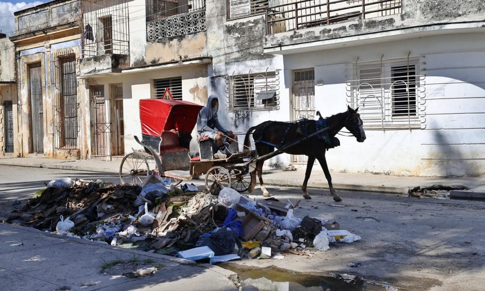 Una persona se transporta en una carreta frente a escombros y basura este viernes, en Cárdenas (Cuba). EFE/ Ernesto Mastrascusa