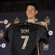 La estrella del fútbol surcoreano Son Heung-min sostiene la camiseta de Los Angeles Football Club (LAFC), durante su presentación como jugador del club de la MLS. EFE/EPA/CAROLINE BREHMAN