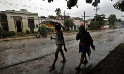 Personas se protegen de la lluvia este martes, en Santiago de Cuba (Cuba). EFE/ Ernesto Mastrascusa