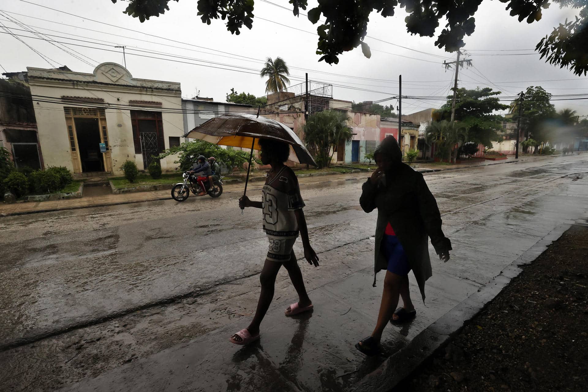 Personas se protegen de la lluvia este martes, en Santiago de Cuba (Cuba). EFE/ Ernesto Mastrascusa