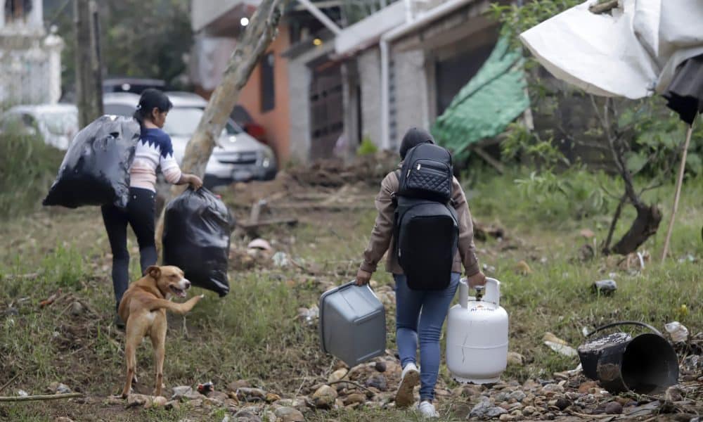 Personas caminan con sus pertenencias en una zona afectada por las fuertes lluvias en Huauchinango (México). EFE/ Hilda Ríos
