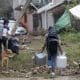 Personas caminan con sus pertenencias en una zona afectada por las fuertes lluvias en Huauchinango (México). EFE/ Hilda Ríos