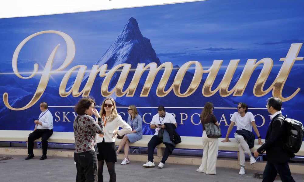 La gente se sienta frente a una pancarta de Paramount. EFE/EPA/Sebastien Nogier