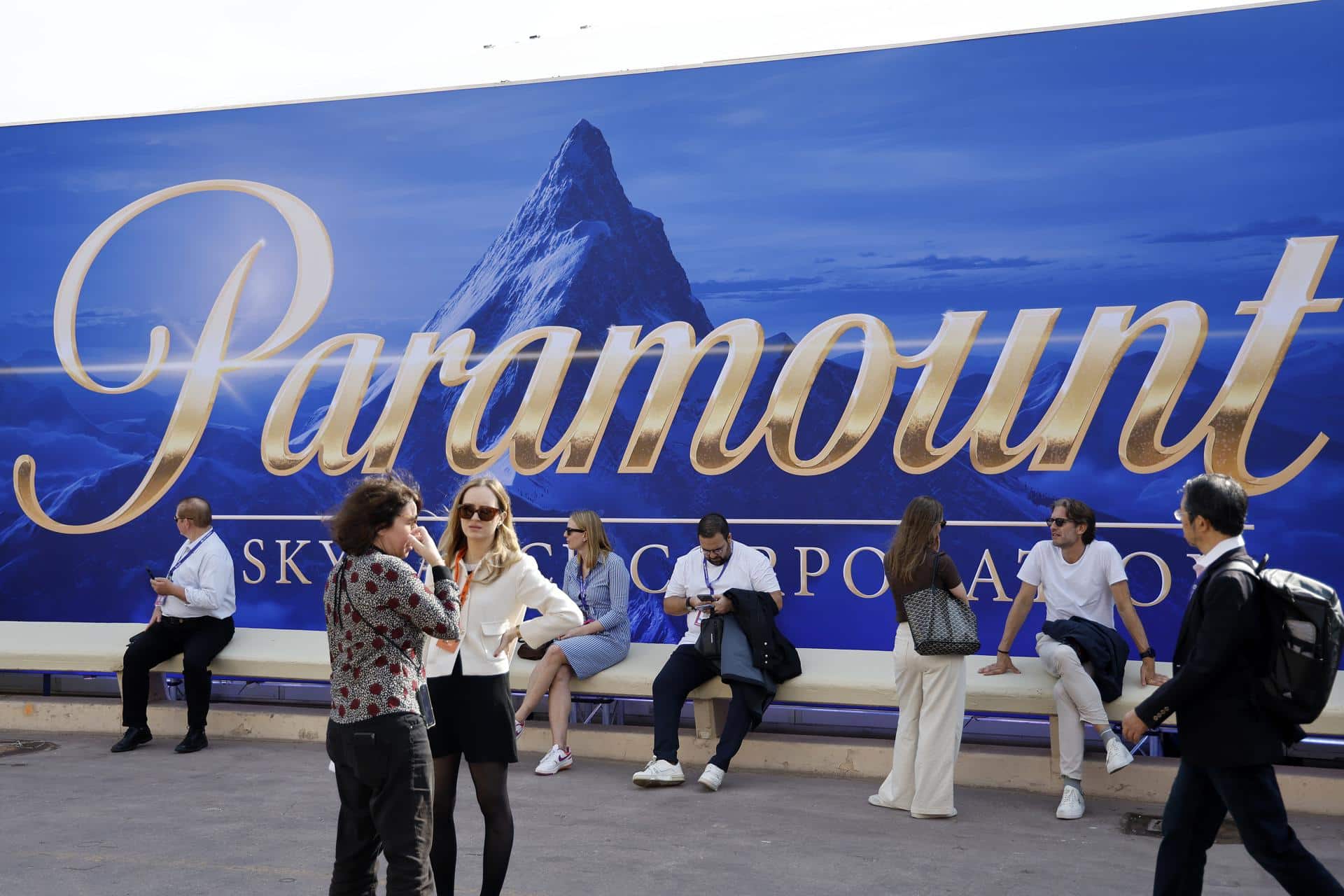 La gente se sienta frente a una pancarta de Paramount. EFE/EPA/Sebastien Nogier