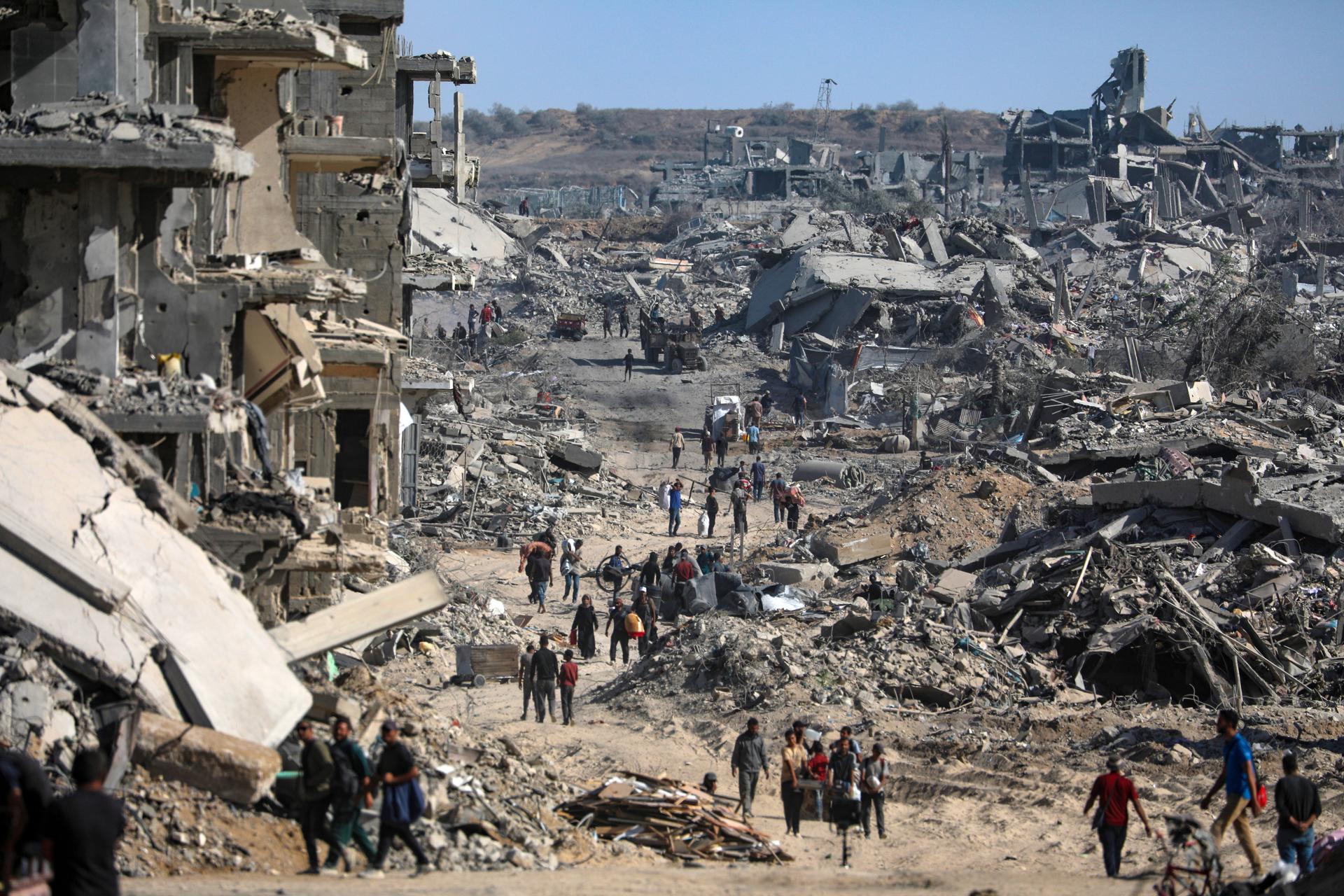 Foto del pasado día 11 de octubre en la que se ve a desplazados internos en Gaza caminando entre los escombros y los edificios destrozados de Ciudad de Gaza. EFE/EPA/MOHAMMED SABER