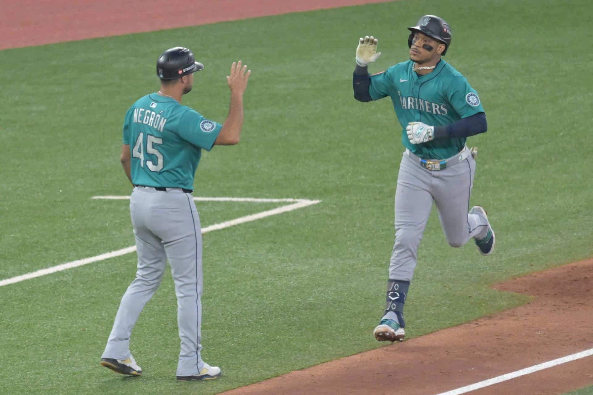 Jorge Polanco (d) es felicitado por el entrenador de tercera base de los Marineros de Seattle, Kristopher Negron, tras conectar su segundo jonrón de tres carreras este lunes en el segundo juego de la Serie de Campeonato de la Liga Americana de la MLB contra los Azulejos de Toronto. EFE/EPA/EDUARDO LIMA