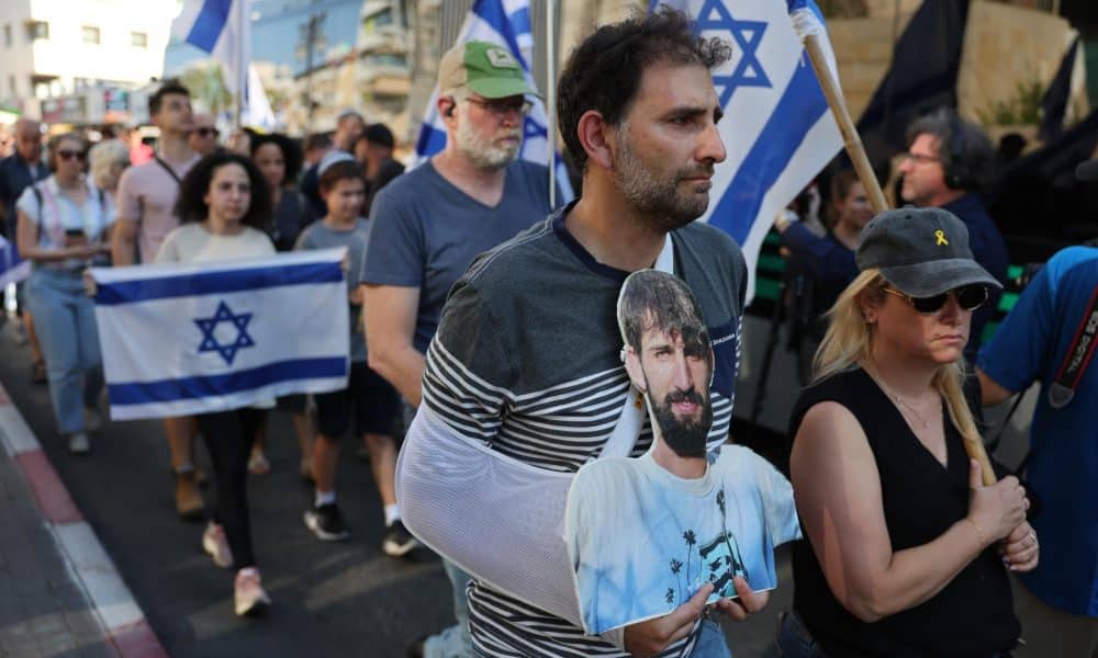 Un hombre porta una foto del difunto rehén israelí Guy Illouz mientras los dolientes escoltan su ataúd durante su procesión fúnebre en Rishon LeZion, Israel, el 15 de octubre de 2025. EFE/ABIR SULTAN