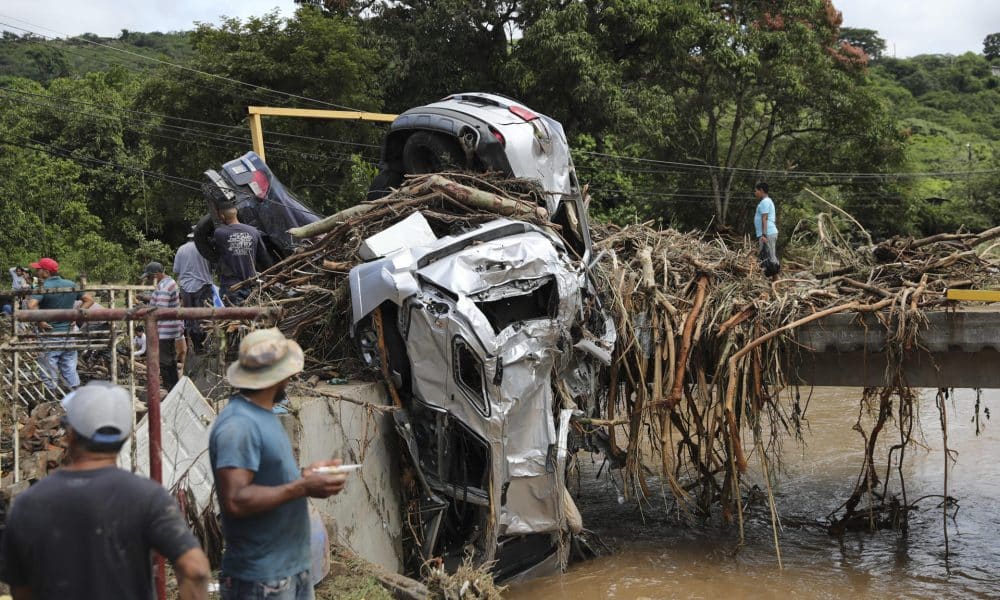 Un grupo de personas observa vehículos arrastrados por la corriente del río este viernes, al este de Tegucigalpa (Honduras). EFE/ Gustavo Amador