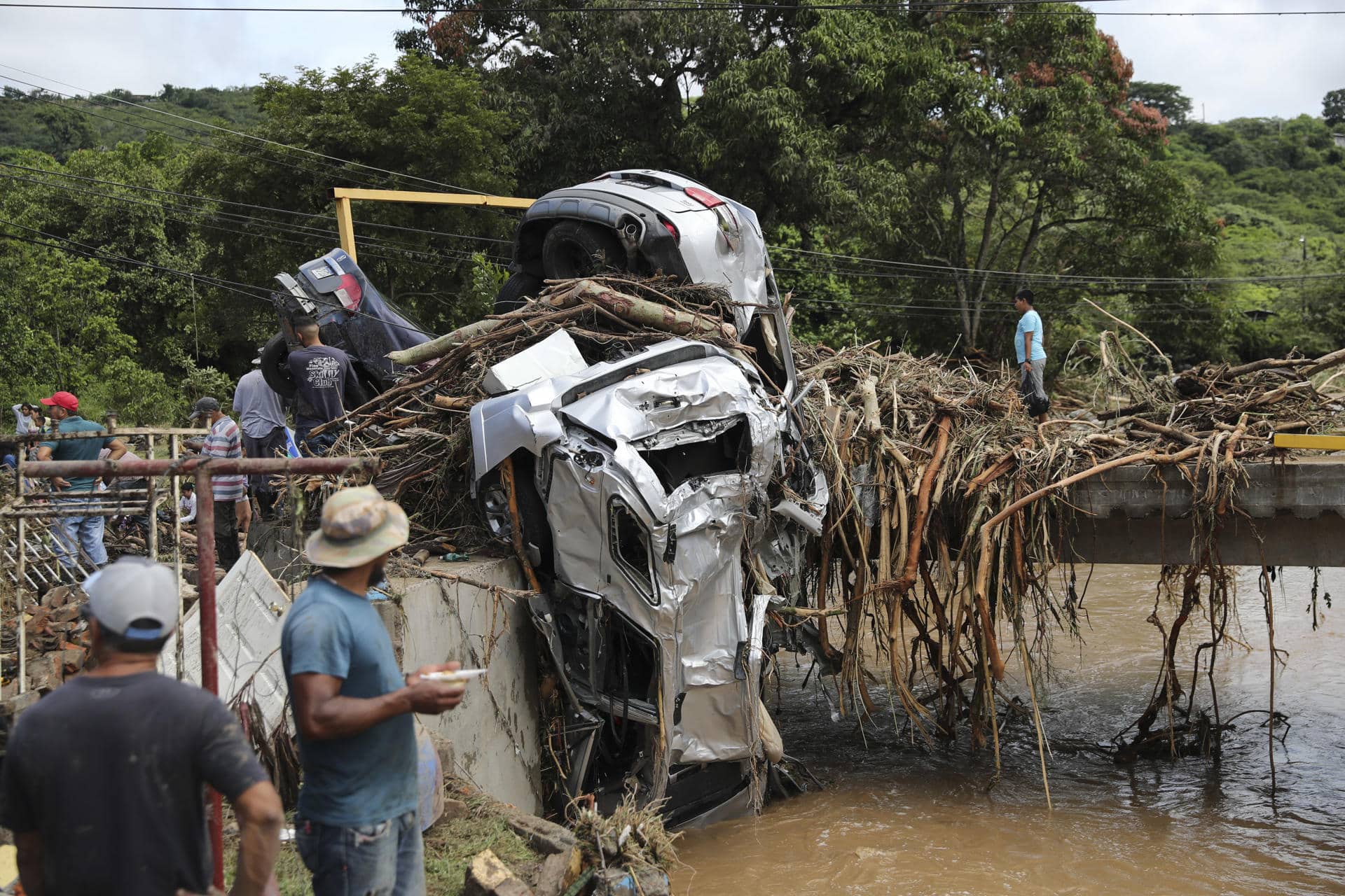 Un grupo de personas observa vehículos arrastrados por la corriente del río este viernes, al este de Tegucigalpa (Honduras). EFE/ Gustavo Amador