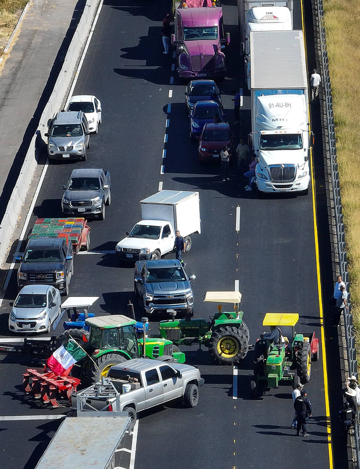 Fotografía aérea que muestra vehículos de carga estacionados durante un bloqueo de agricultores en la carretera que comunica de León a Aguascalientes este martes, en León (México). Agricultores del estado de Guanajuato (centro del país) bloquearon diversas carreteras tras no llegar a un acuerdo con el gobierno federal para establecer un precio mínimo a la tonelada de maíz y el sorgo. EFE/ Luis Ramírez