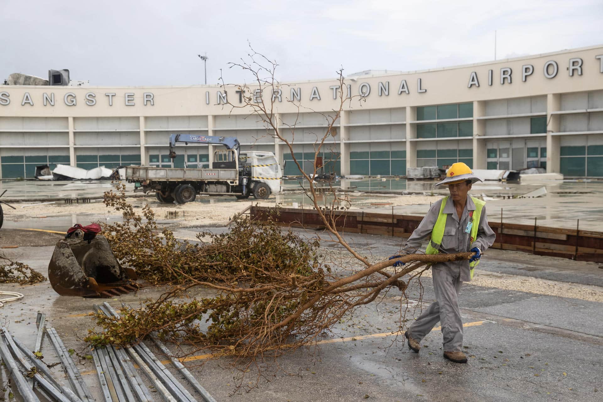 Un obrero fue captado este sábado, 1 de noviembre, al trasladar la rama de un árbol arrancada por el huracán Melissa, frente al Aeropuerto Internacional Sangstereste, en Montego Bay (Jamaica). EFE/Orlando Barría