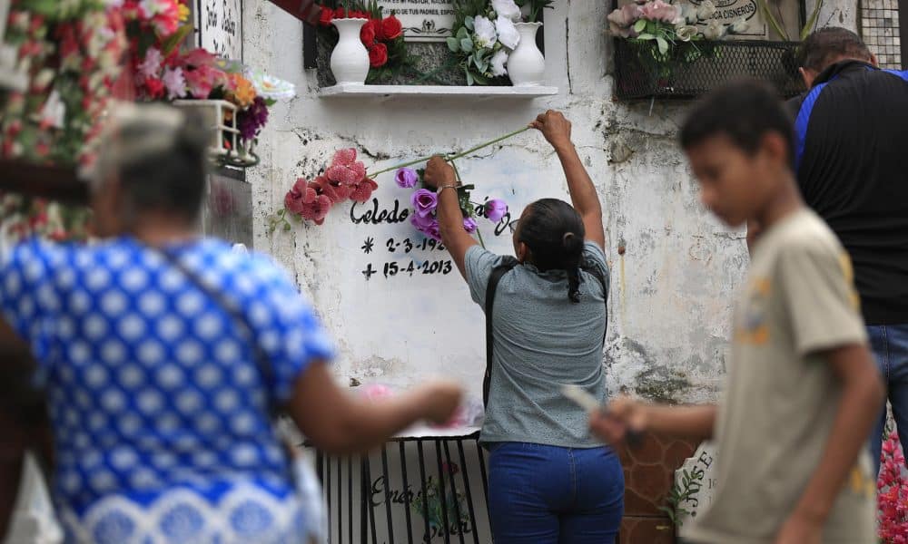 Una mujer pone flores en una tumba con motivo del Día de Muertos este domingo, en el cementerio municipal en La Chorrera (Panamá). EFE/ Bienvenido Velasco