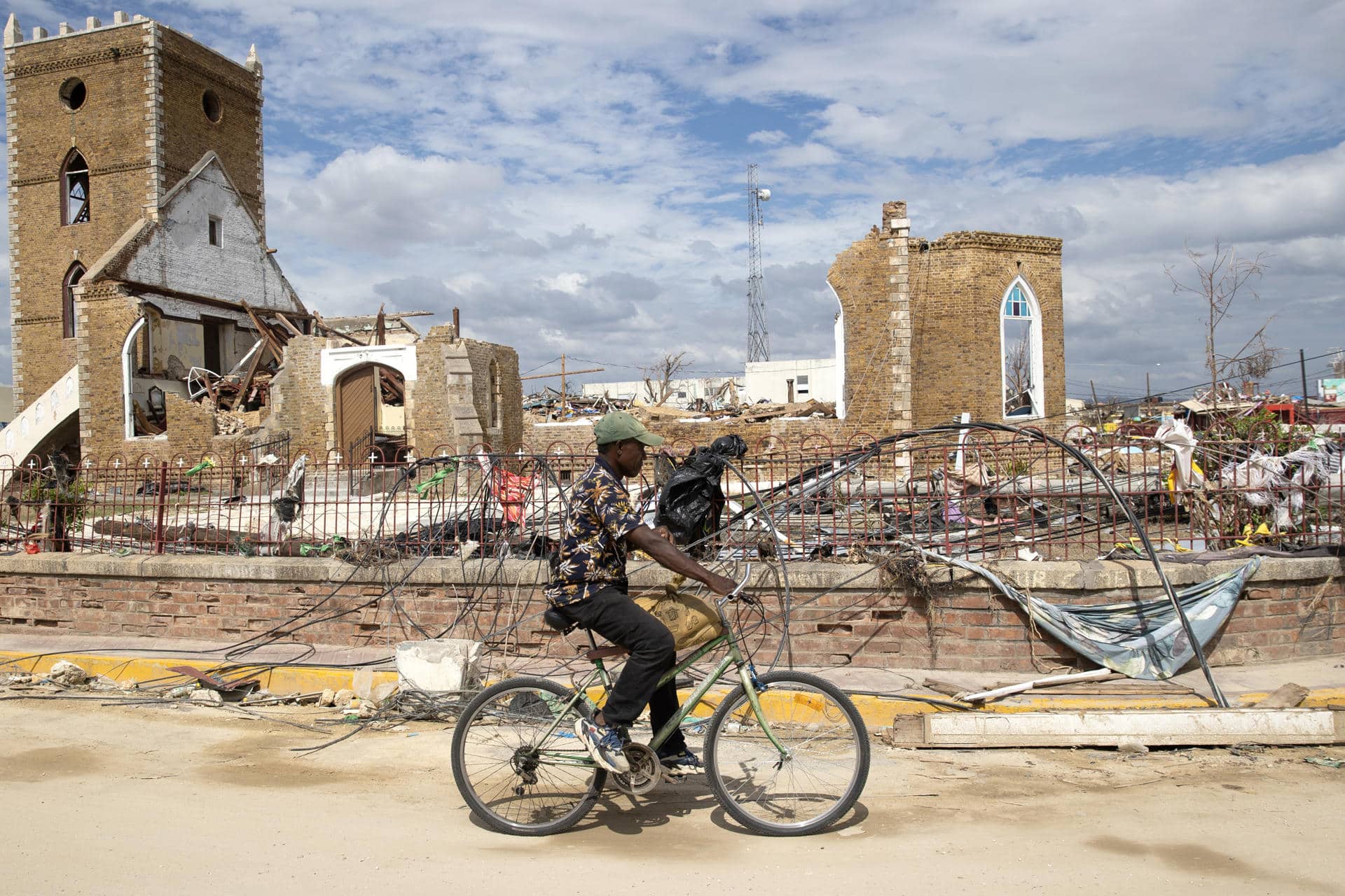 Un hombre recorre en bicicleta frente a escombros de una catedral causados por el huracán Melissa en Black River (Jamaica). Imagen de archivo. EFE/ Orlando Barría
